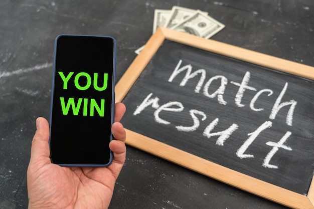 3 Chiến Lược Đặt Cược Nhỏ Giúp Bạn Thắng Lớn Tuyệt Vời 4 pix hand with smartphone screen with congratulations victory chalkboard with text match result dollar bills background 182793 470.jpg.jpg